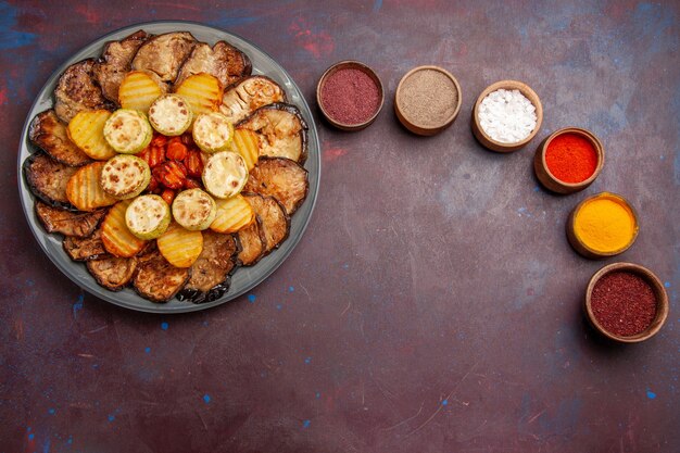 Free photo top view baked vegetables potatoes and eggplants with different seasonings on dark space