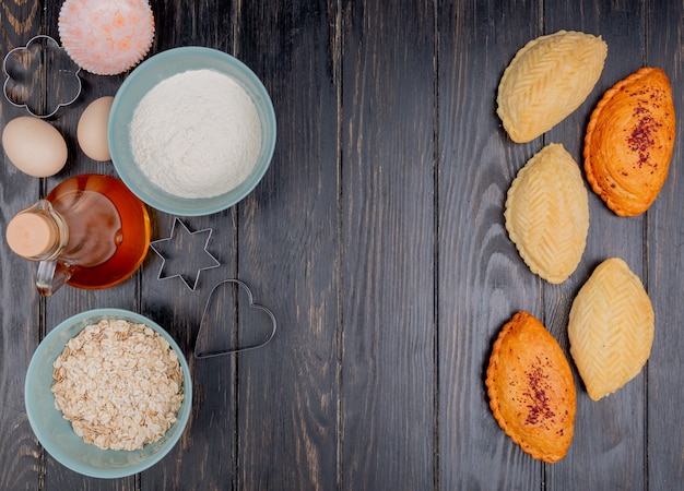 Top view of bakery products as shakarbura with flour oat flakes butter on wooden background with copy space