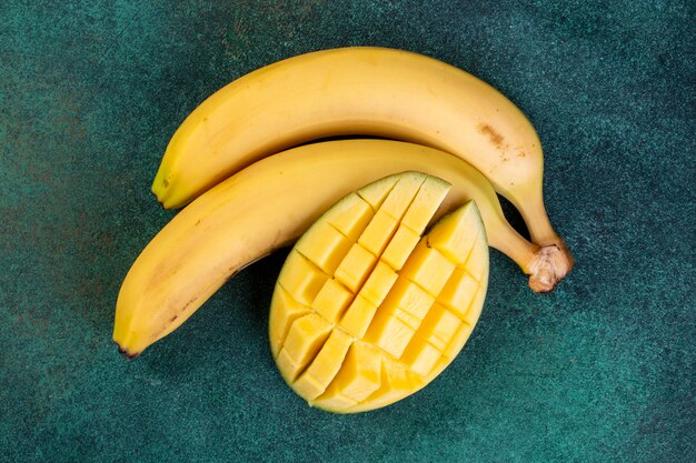 top view bananas with chopped mangoes on a green table