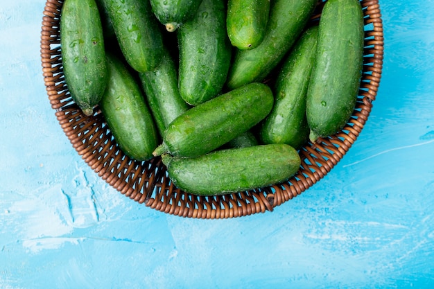 Free photo top view of basket full of whole cucumbers on blue surface