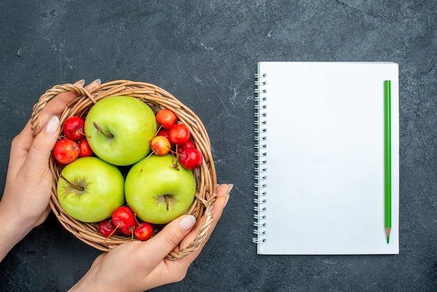 Free photo top view basket with fruits apples and sweet cherries on dark grey surface fruits berry composition freshness tree