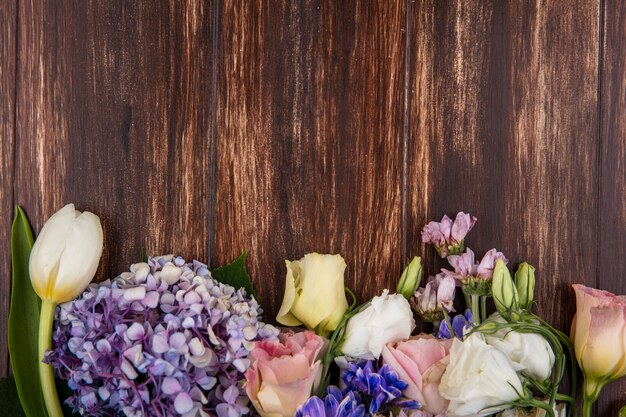 Top view of beautiful flowers such as gardenzia tulip roses isolated on a wooden background with copy space