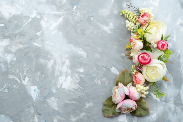 A top view beautiful flowers with leaves on bright desk, flower plant color