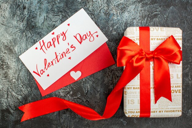 Top view of beautiful gift box tied with red ribbon for Valentines Day on icy dark background