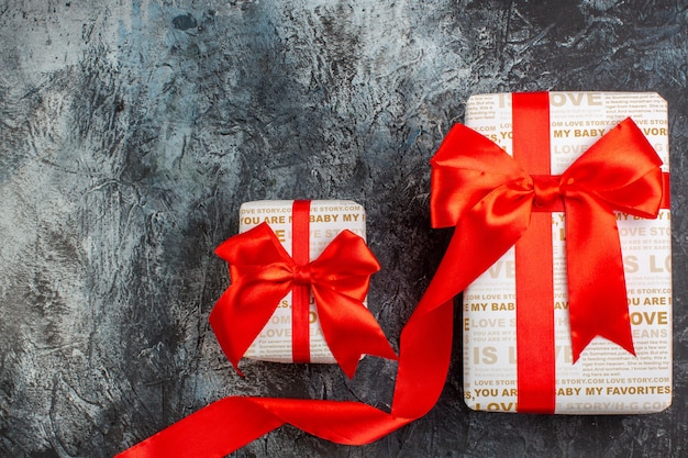 Top view of beautiful gift boxes tied with red ribbon in different sizes on icy dark background