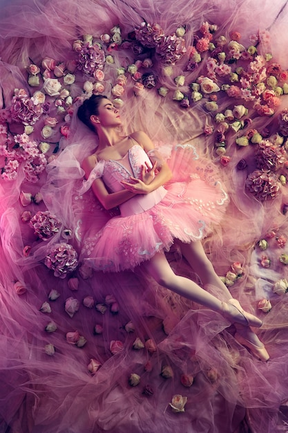 Top view of beautiful young woman in pink ballet tutu surrounded by flowers