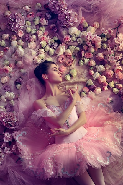 Top view of beautiful young woman in pink ballet tutu surrounded by flowers