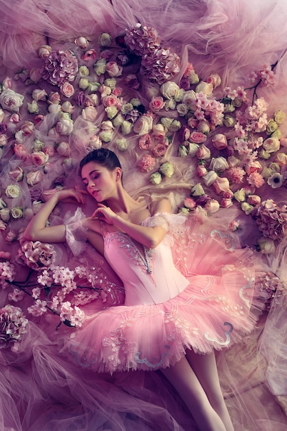 Top view of beautiful young woman in pink ballet tutu surrounded by flowers