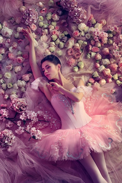 Top view of beautiful young woman in pink ballet tutu surrounded by flowers