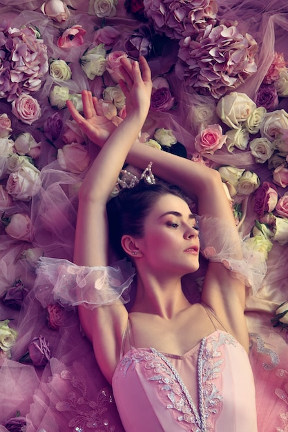 Top view of beautiful young woman in pink ballet tutu surrounded by flowers