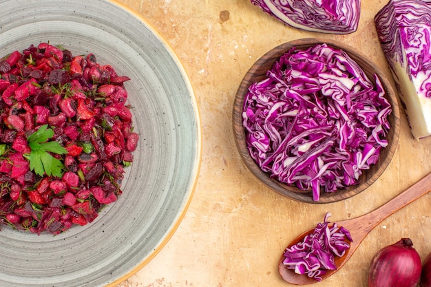 Free photo top view beet salad on a plate with red onions and chopped red cabbage in a bowl on a wooden table