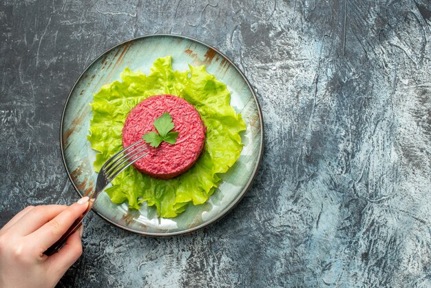 Top view beet salad on platter fork in woman hand on grey table with copy place