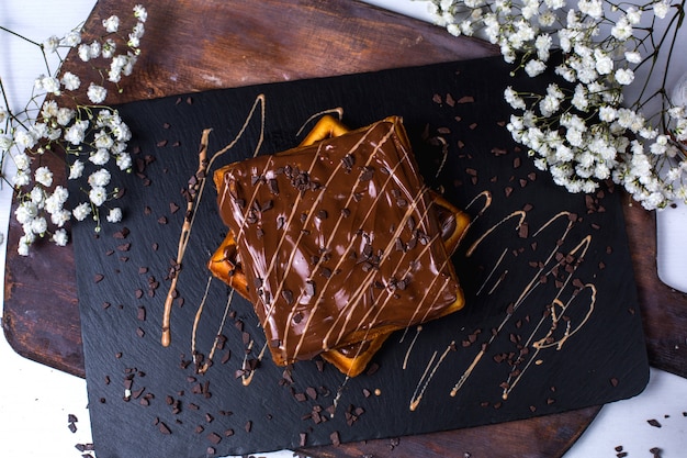 Top view of belgian waffle with chocolate on a wooden board