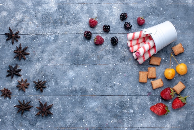 top view of berries and biscuits with pink stick candies on bright desk, fruit berry cookie biscuit