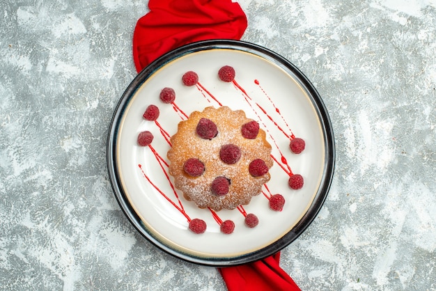 Top view berry cake on white oval plate red shawl on grey surface