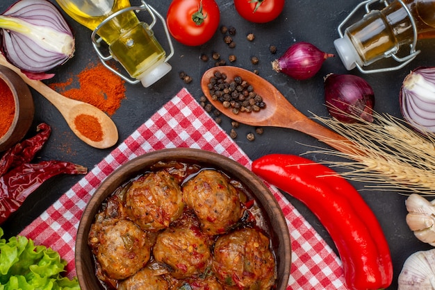 Free photo top view big meatball soup in bowl red pepper powder in small bowl lettuce onions bottle on table