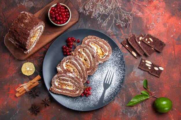 Top view of biscuit rolls with red fruits on dark surface