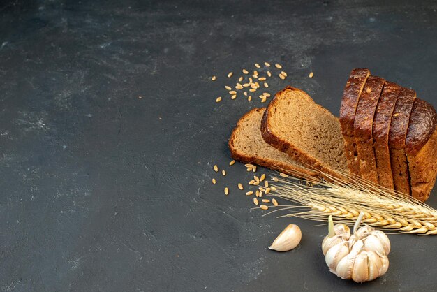 Top view of black bread slices spikes garlics on the right side on black background