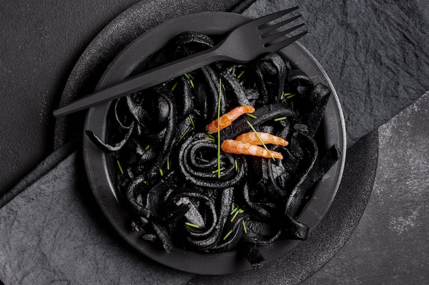 Free photo top view black shrimp pasta with fork