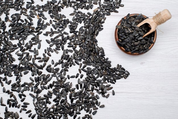 A top view black sunflower seeds fresh and tasty all over the white background grain sunflower seed granule