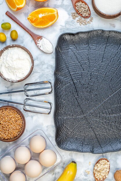 Top view of black tray and fresh oranges spoon brown rice in a pot eggs on ice background