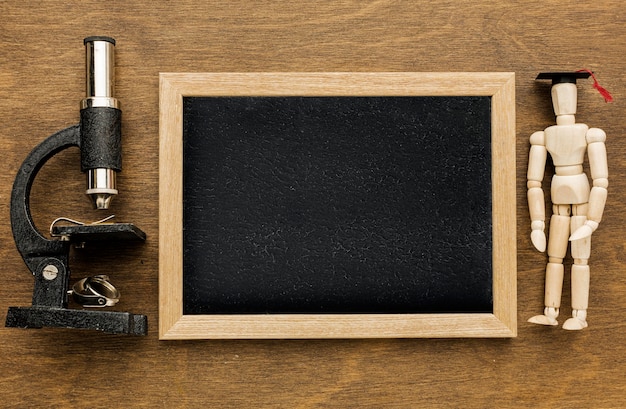 Top view of blackboard with microscope and wooden figurine