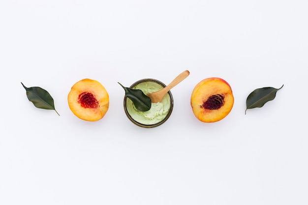 Top view of body butter and nectarines on plain background