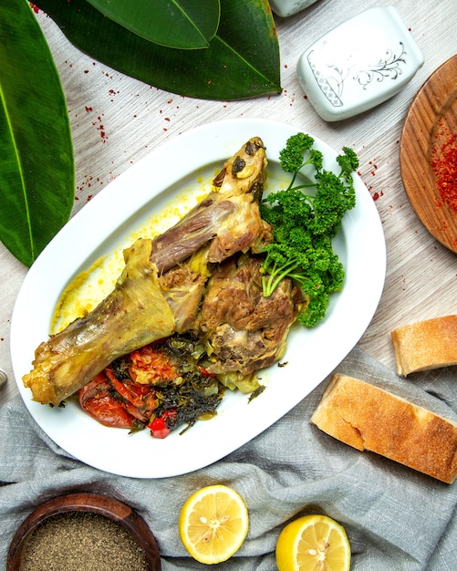 Free Photo top view boiled lamb leg with vegetables with spices lemon slices and bread