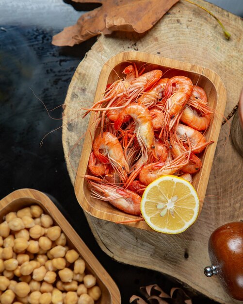 Top view of boiled shrimp served with lemon half in bamboo serving