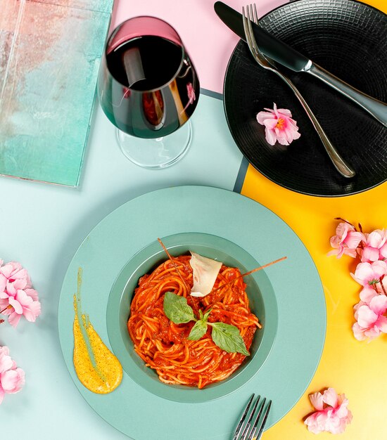 Top view of bolognese spaghetti topped with basil in turquoise plate