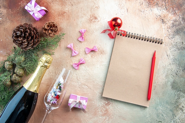 Top view bottle of champagne with little presents and notepad on light xmas photo new year color gift alcohol