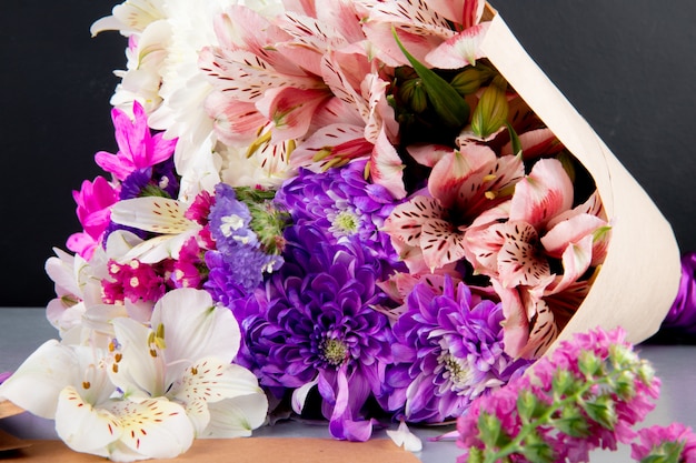 Free photo top view of a bouquet of white and pink color alstroemeria and chrysanthemum flowers in craft paper on dark background