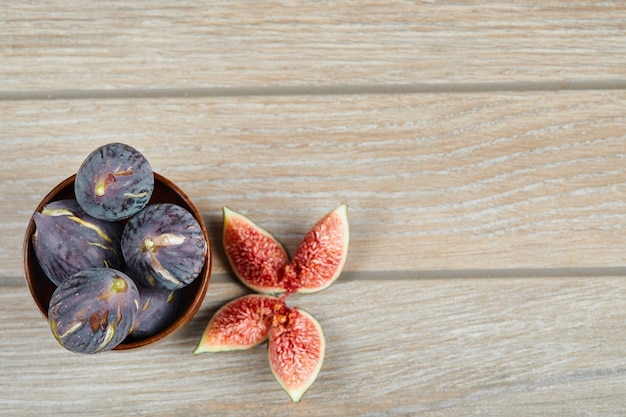 Free Photo top view of the bowl of black figs and slices of figs on a wooden table