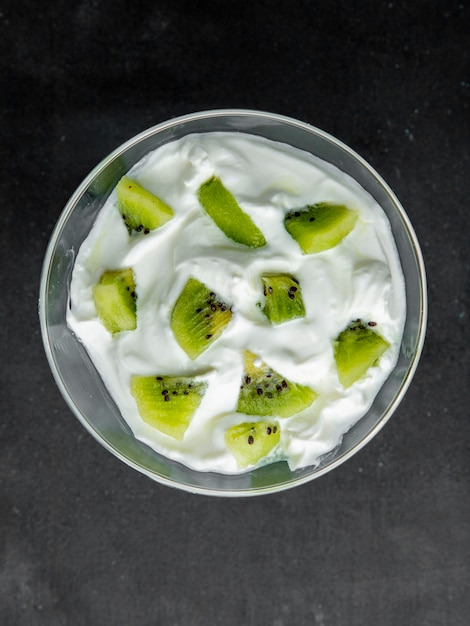 Top view of bowl full of kiwi yogurt on black surface