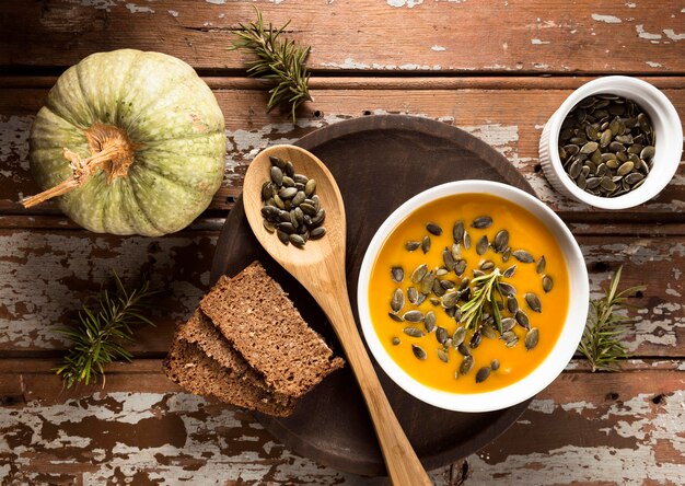 Top view of bowl with autumn squash soup with seeds and bread