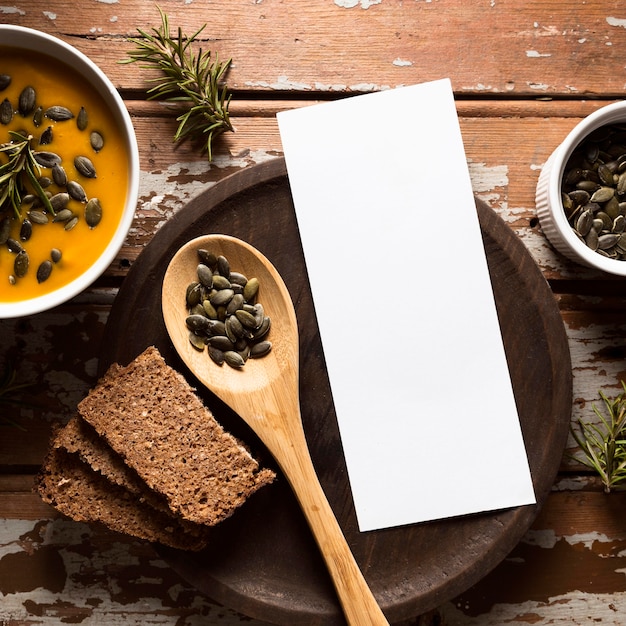 Top view of bowl with autumn squash soup with seeds and wooden spoon