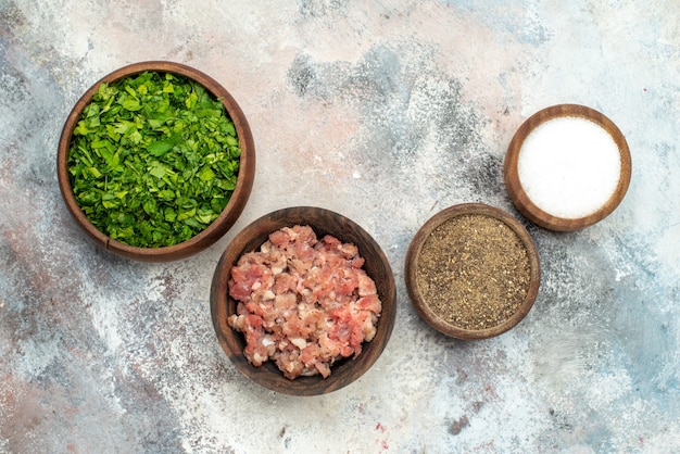 Free photo top view bowls with different spices greens meat on nude background free space food photo