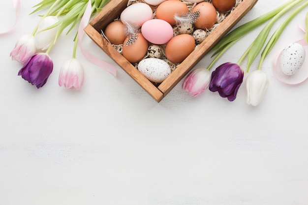 Top view of box with eggs for easter and colorful tulips