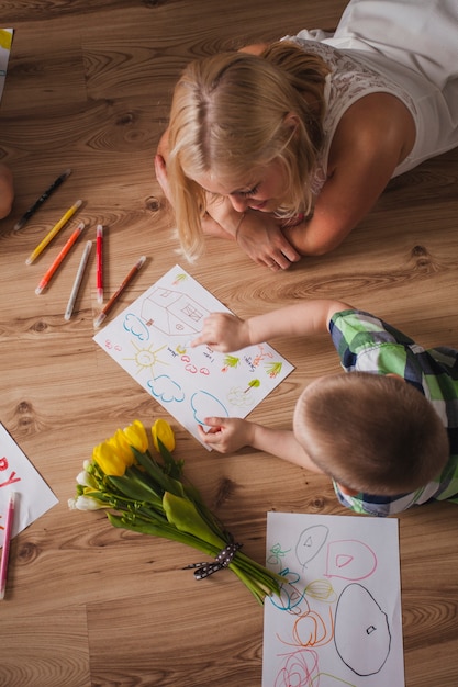 Top view of boy pointing a drawing to his mother