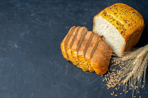 Top view bread slices wheat spikes and grains on dark table with free space