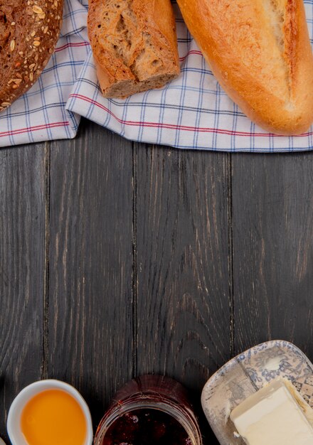 top view of breads as seeded vietnamese black baguettes on cloth with butters and jam on wooden table with copy space