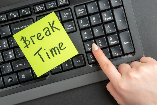 Free photo top view break time written on sticky note on keyboard female hand on end key on black surface