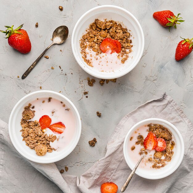 Top view breakfast bowls with granola and milk