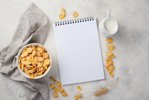 Free Photo top view of breakfast corn flakes with notebook and milk