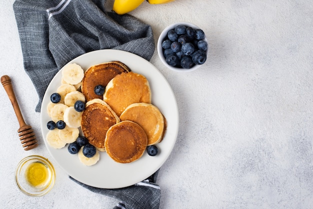 Free photo top view of breakfast pancakes on plate with honey and blueberries