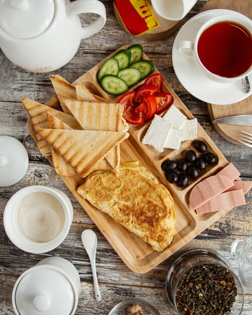 Top view of breakfast setup with omelet toast cucumber tomato cheese olive