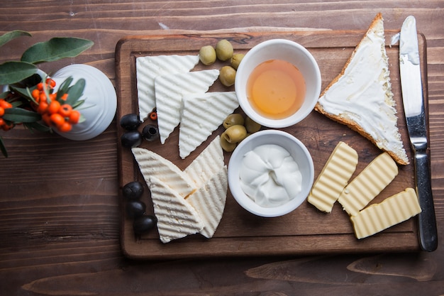 Top view breakfast with cheese and olive and honey in board cookware