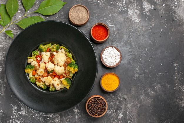 Free Photo top view broccoli and cauliflower salad on black oval plate different spices in small bowls on dark surface free place