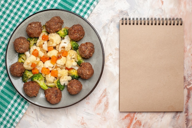 Free Photo top view broccoli and cauliflower salad and meatball on plate green and white checkered napkin a notebook on nude isolated background