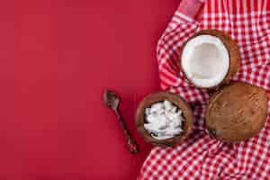 Free photo top view of brown coconuts with pulps of coconut in a wooden bowl with spoon on red and white checked tablecloth on red with copy space